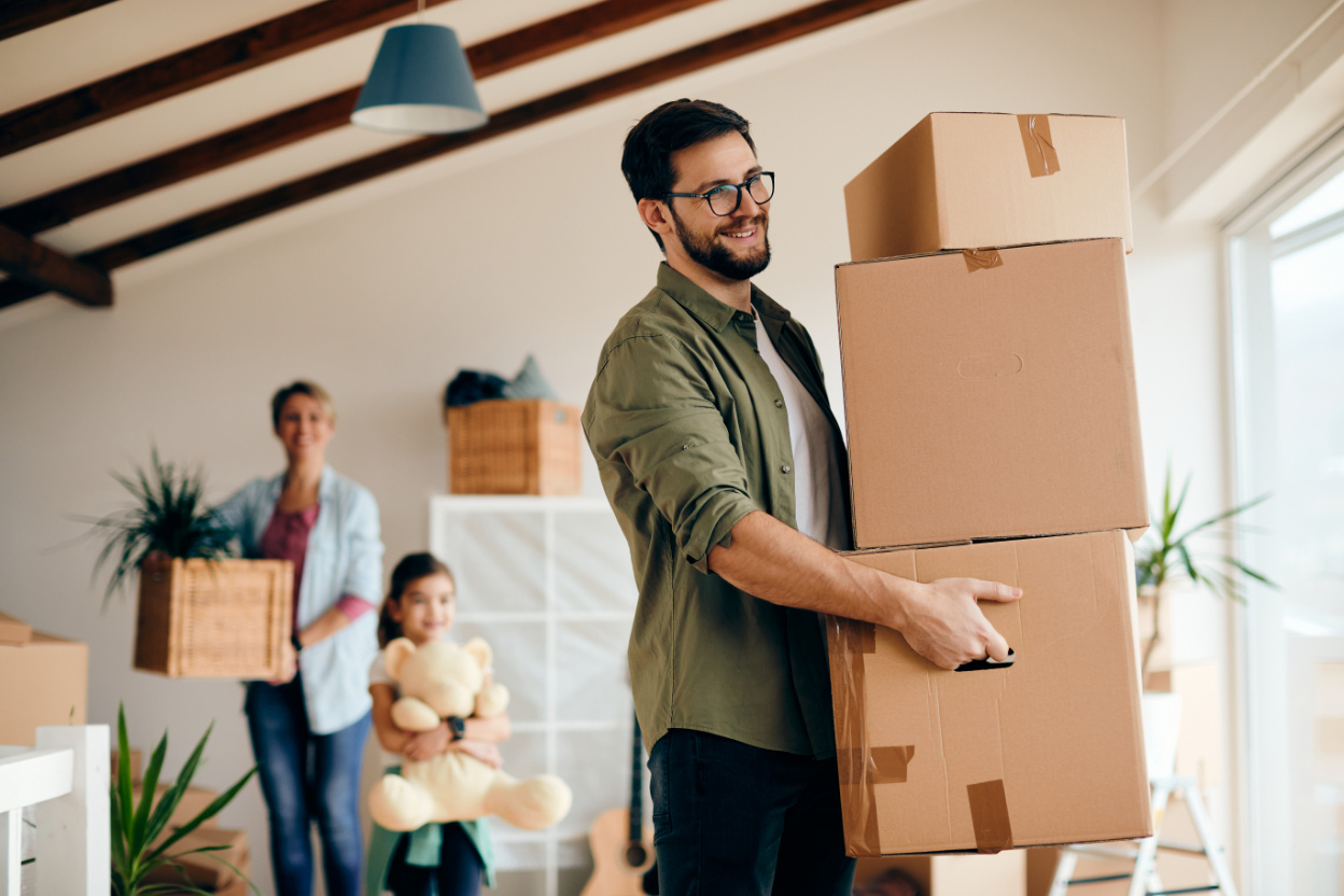 Happy father carrying stack cardboard